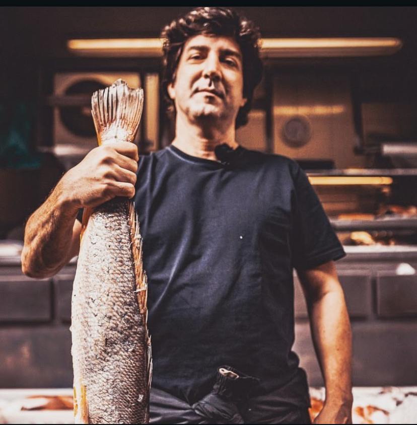 Luiz Campiglia na cozinha, segurando um peixe inteiro